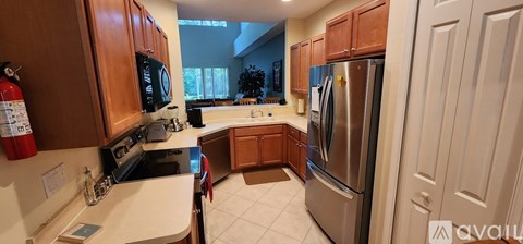 A kitchen with wooden cabinets and a stainless steel refrigerator.