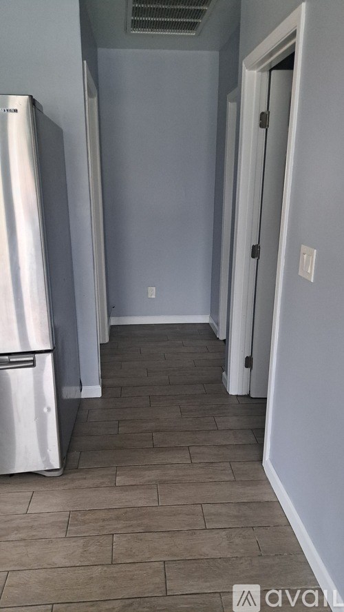 A white refrigerator is in a kitchen with a white door.