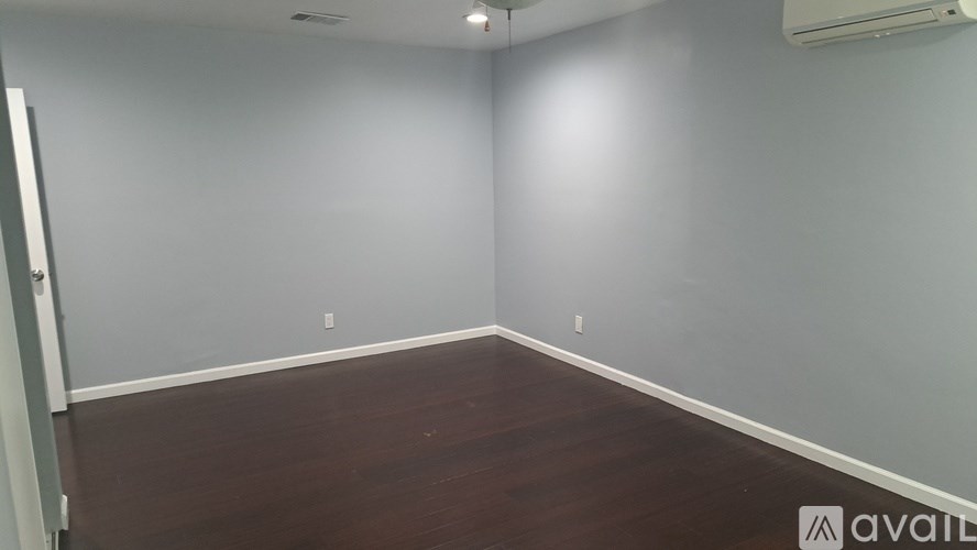 A room with wooden flooring and white walls.