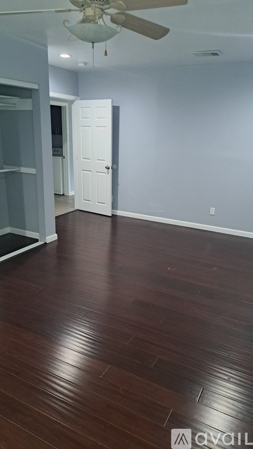 A room with a white ceiling fan and wooden floors.
