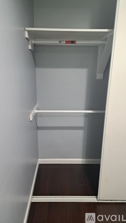A small, empty closet with a white door and shelves.