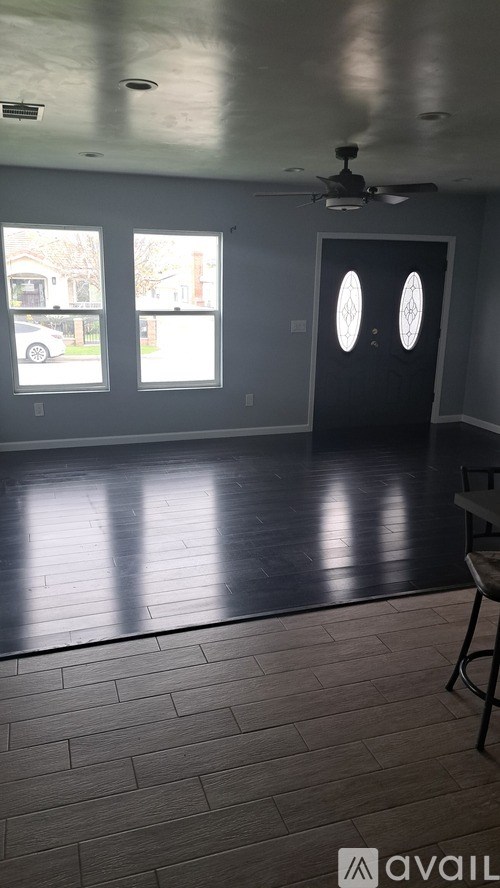 A room with a ceiling fan and a black door.