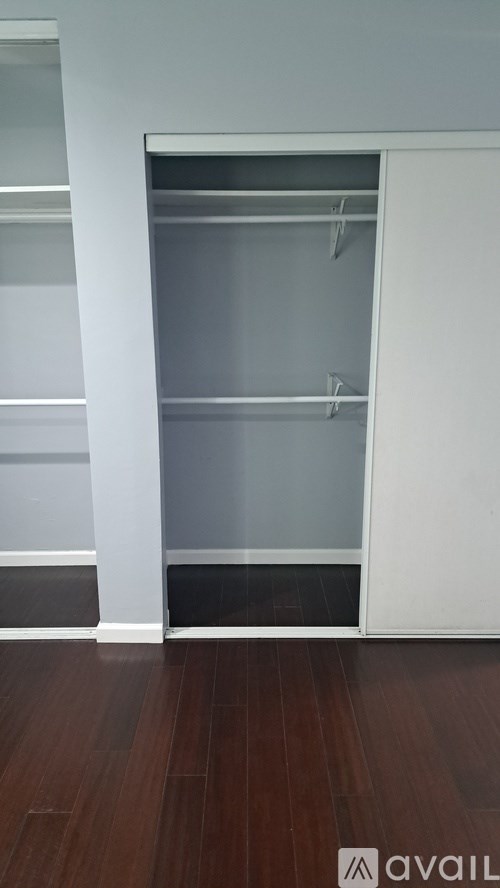 A white closet with a shelf and a wooden floor.