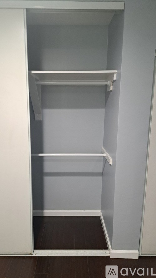 A white closet with three shelves and a door open.