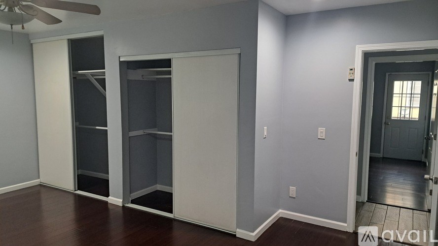 A room with a ceiling fan and a door leading to another room.