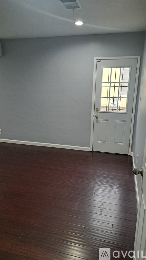 A room with a white door and wooden floor.