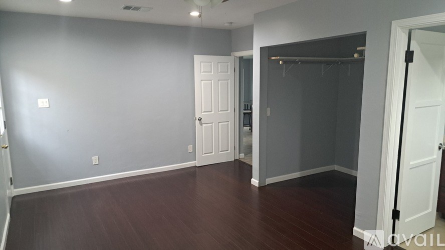 A room with a white door and a wooden floor.