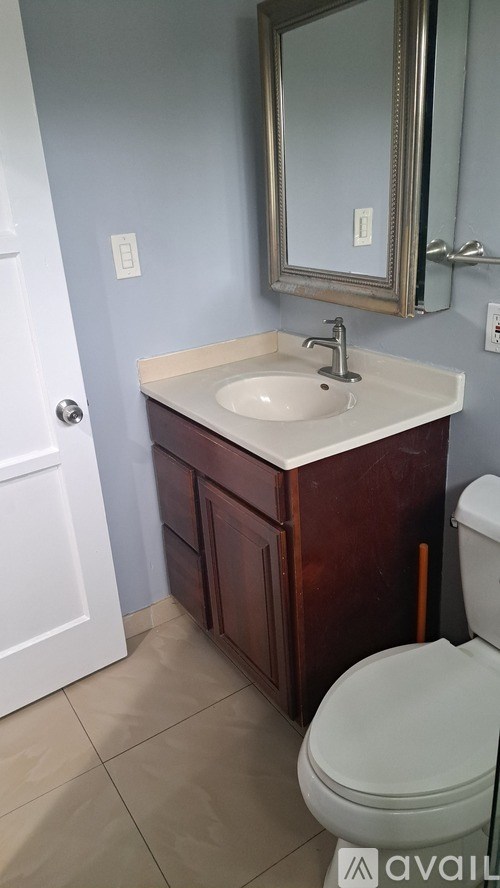 A bathroom with a sink, toilet and mirror.