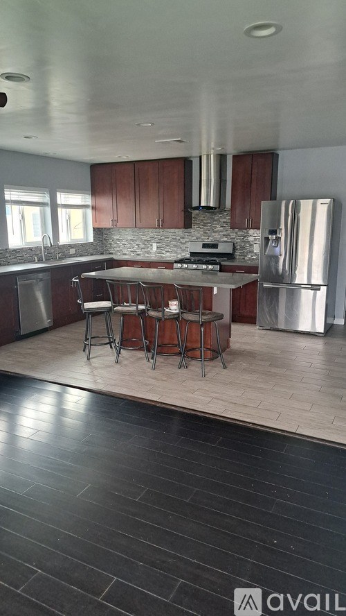 A kitchen with a bar stool and a fridge.
