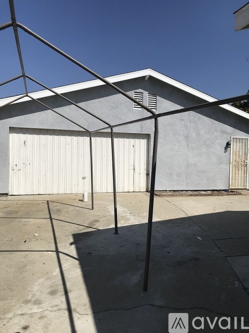 A metal structure stands in front of a grey building.