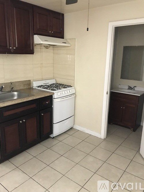 A kitchen with a white stove and dark brown cabinets.