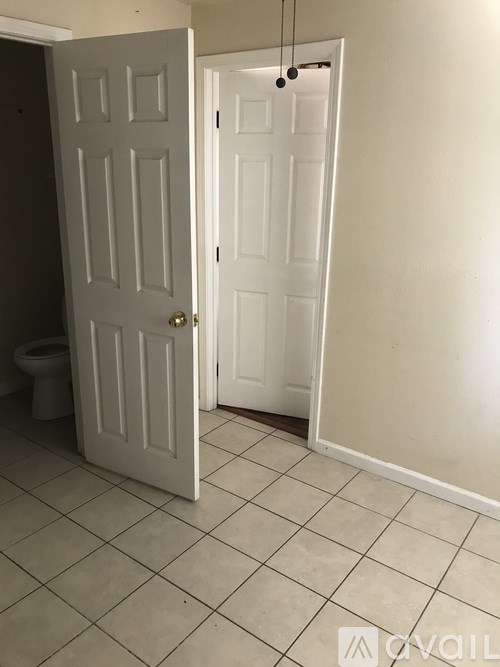 A room with a toilet and two doors.
