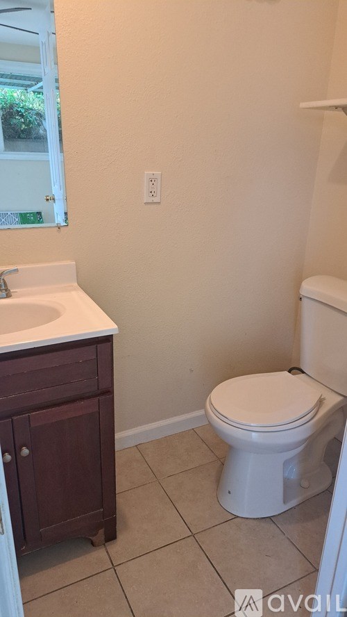 A white toilet sits in a bathroom next to a sink.