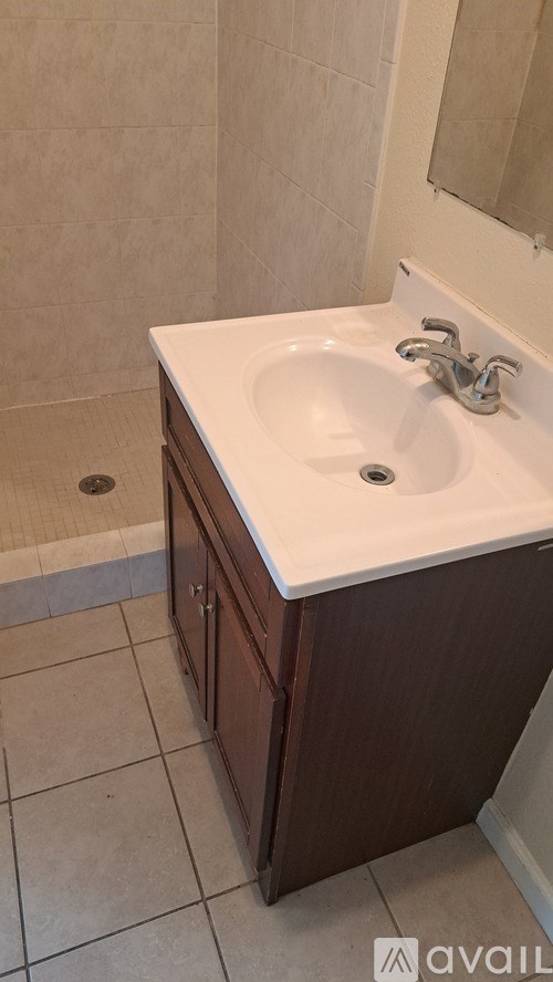 A bathroom sink with a brown cabinet and a white counter.