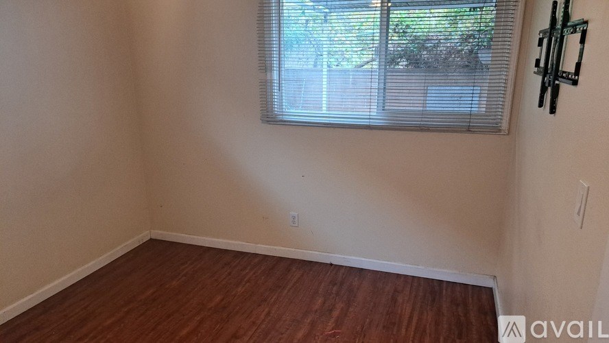 A room with wooden flooring and a window with blinds.