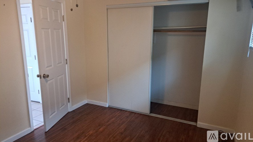 A room with a white door and a white closet with a shelf.