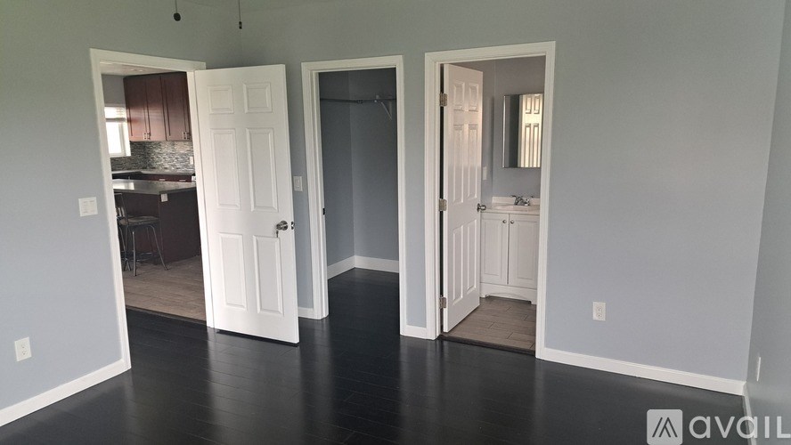 A room with three doors and a bathroom visible through one of them.