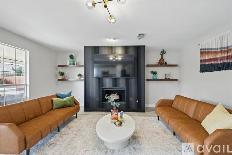A living room with a brown leather couch, a white coffee table, and a black fireplace.