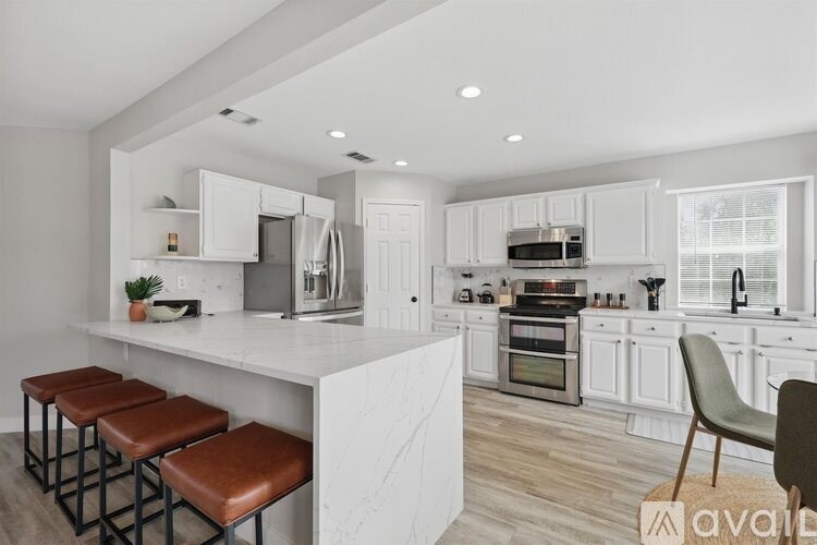 A modern kitchen with white cabinets and a marble island.