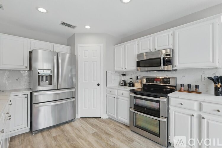 A modern kitchen with white cabinets and stainless steel appliances.