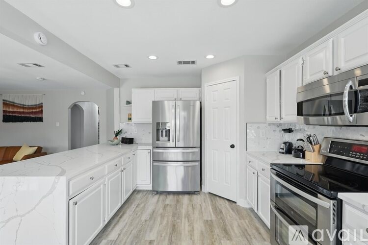 A modern kitchen with white cabinets and stainless steel appliances.