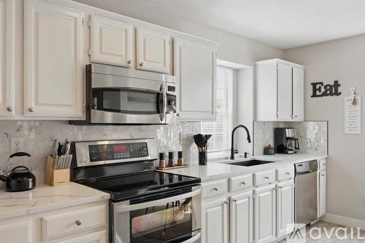 A kitchen with white cabinets and appliances.