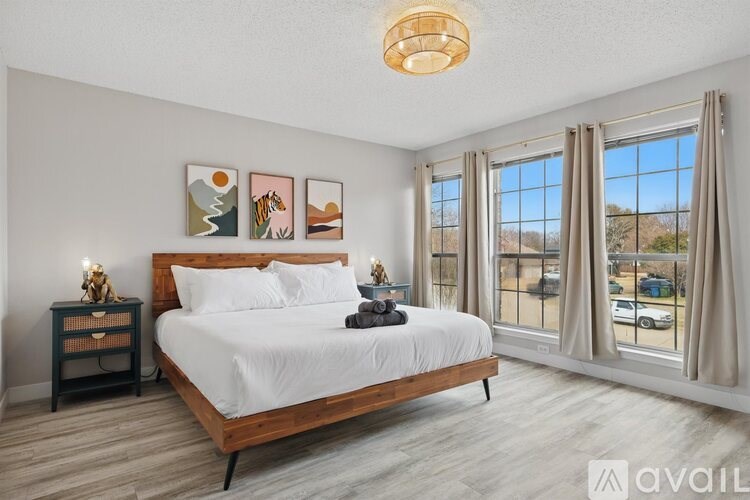 A bedroom with a large bed, a nightstand with a lamp, and pictures on the wall.