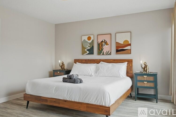 A bedroom with a large bed and a small nightstand with a lamp.