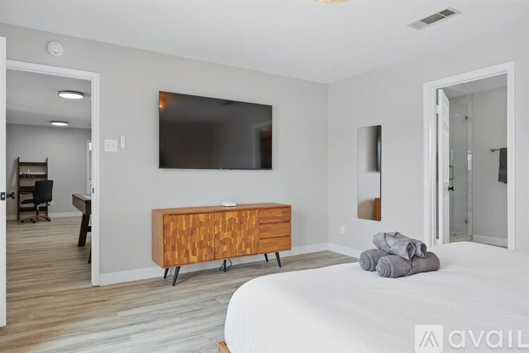 A bedroom with a bed, a dresser, and a television.