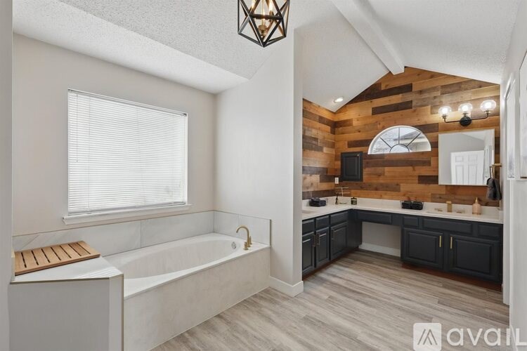 A modern bathroom with a wooden accent wall and a large bathtub.