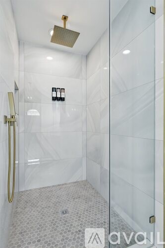 A modern bathroom with a glass shower stall and a gold-framed shower door.