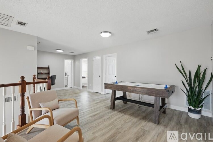 A room with a pool table, chairs, and a plant.