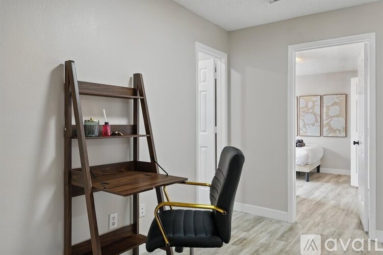 A wooden chair with a black seat and yellow armrests sits in front of a wooden shelf.