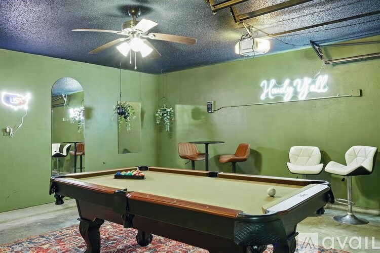 A pool table is in the middle of a room with green walls.