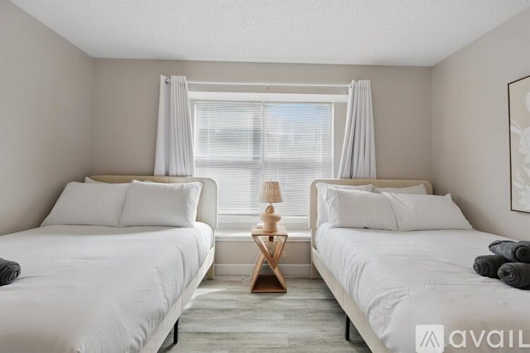 Two beds in a room with a window and a lamp on a table.
