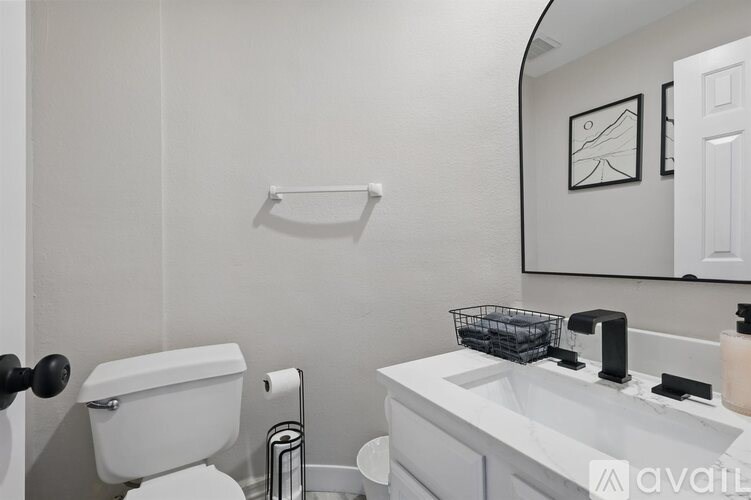A bathroom with a toilet, sink, and mirror.