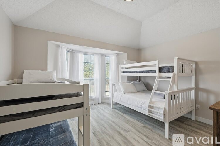 A bedroom with two bunk beds and a window with curtains.