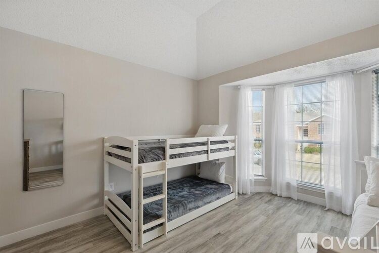 A bedroom with a bunk bed and a window with curtains.