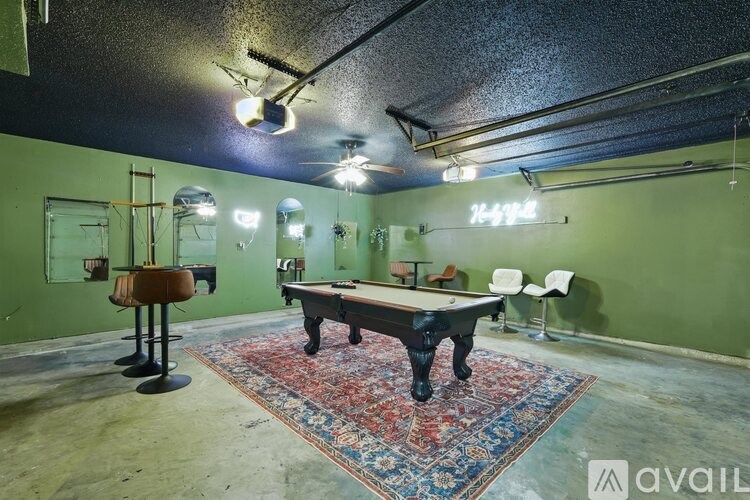 A room with a pool table and a bar stool.