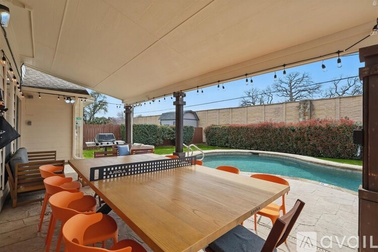 A wooden table with orange chairs is set up under a white canopy.