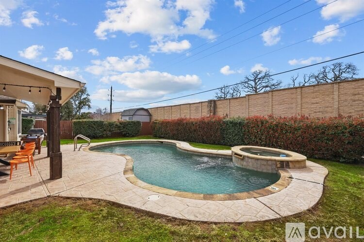 A backyard with a kidney-shaped pool and a patio.