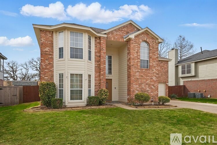 A brick house with a large front yard and a fence.