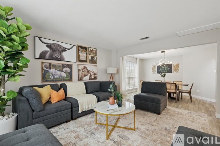 A living room with a grey couch, a black chair, a coffee table, and pictures on the wall.