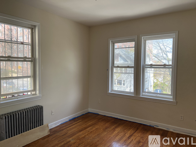 A room with two windows and a radiator on the floor.