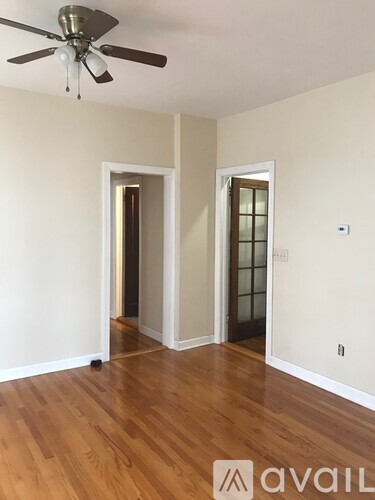A room with a ceiling fan and wood flooring.