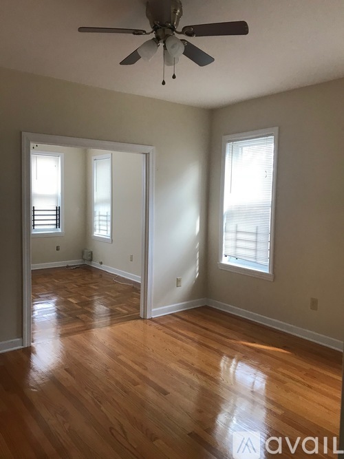 A room with a ceiling fan and wooden floors.