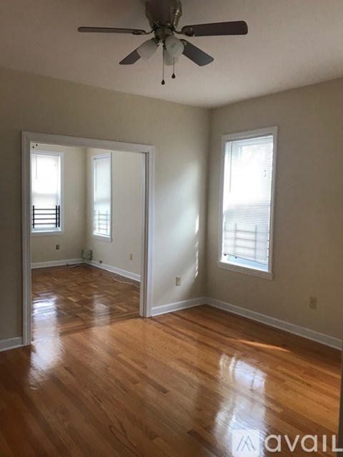 A room with a ceiling fan and wooden floors.