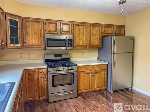 A kitchen with wooden cabinets and a stainless steel refrigerator.