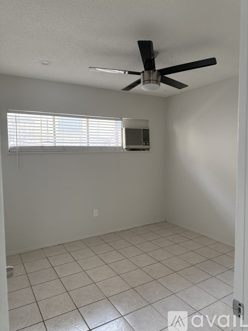 A room with a ceiling fan and a window with blinds.