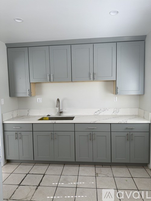 A kitchen with grey cabinets and a marble countertop.